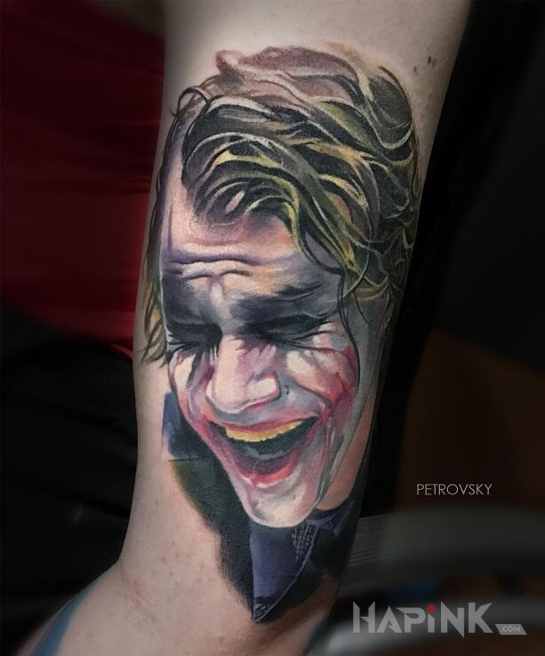 Tattoo Śmiech Jokera in characters motif and realistic style on the upper arm