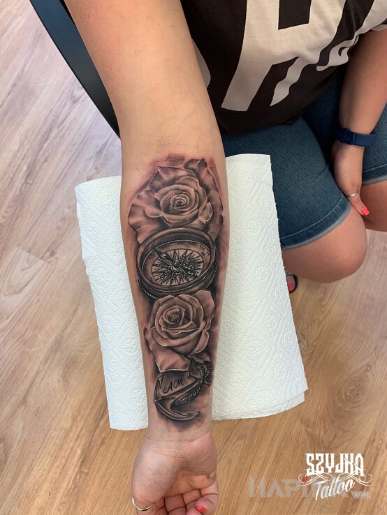 Tattoo Róża wiatrów w otoczeniu róż. ? in black and gray motif and realistic style on the forearm