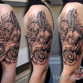 Tattoo Skull in flowers on the upper arm motif: black and gray style: realistic