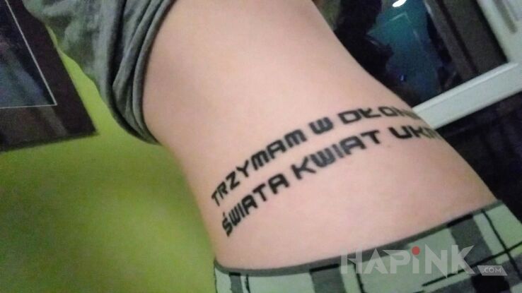 Tattoo Trzymam w dłoniach świata kwiat ukryty in lettering motif on the ribs