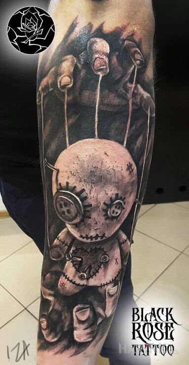 Tattoo Laleczka in dark motif and realistic style on the forearm