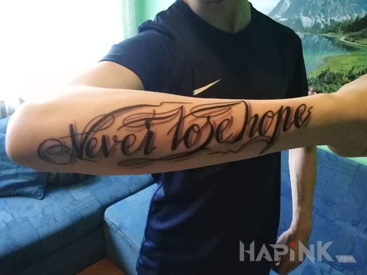 Tattoo Never Lose Hope in lettering motif and calligraphy style on the forearm