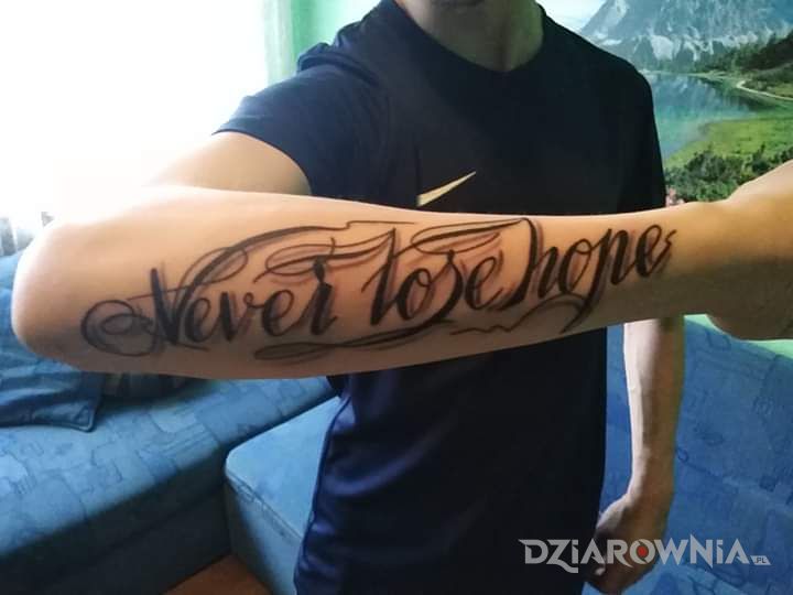 Tatuaż never lose hope w motywie napisy i stylu kaligrafia na przedramieniu