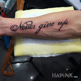 Tattoo Never ??? on the forearm motif: lettering style: calligraphy
