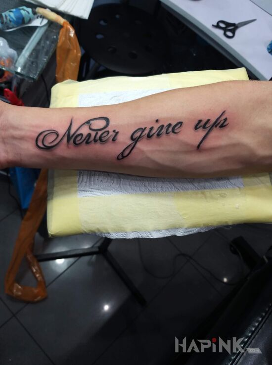 Tattoo Never ??? in lettering motif and calligraphy style on the forearm