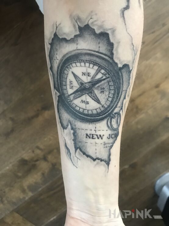 Tattoo Kompas in black and gray motif and realistic style on the forearm