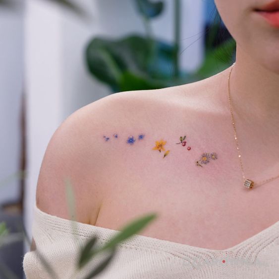 Tatuaż kilka różnych kwiatków w motywie kwiaty i stylu minimalistyczne na obojczyku