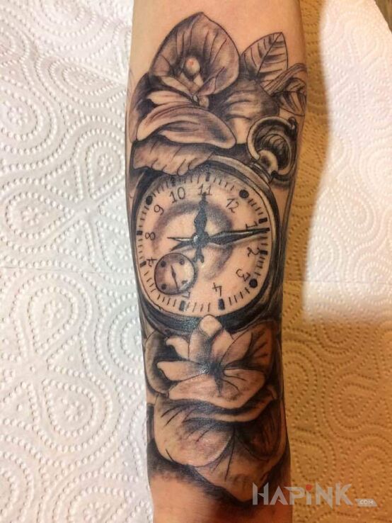 Tattoo Pierwszy - zegar z kwiatami in black and gray motif and realistic style on the forearm