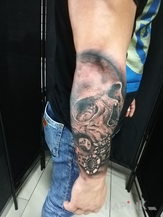 Tattoo Czaszka z żetonami do gry tattoo in casino motif and realistic style on the forearm
