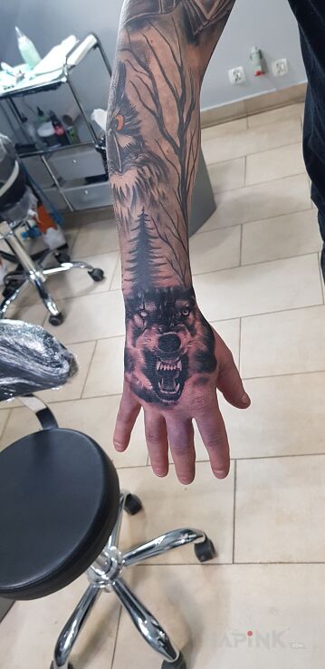 Tattoo Wolf in black and gray motif and realistic style on the hand