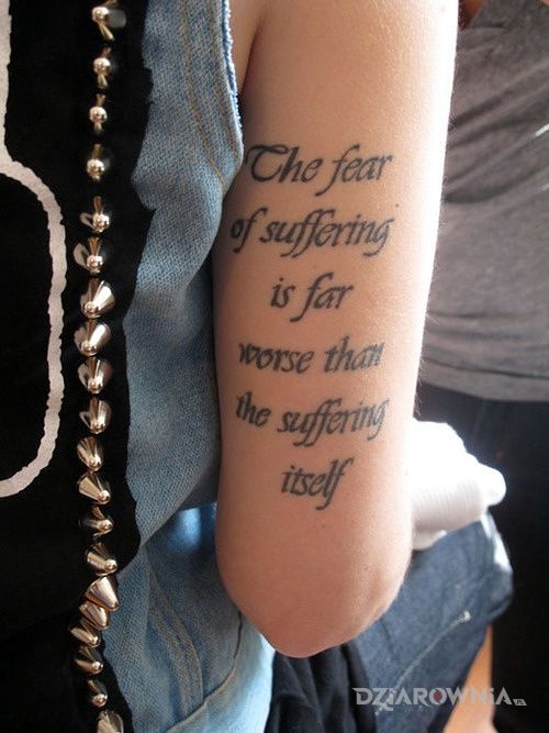 Tatuaż strach przed cierpieniem w motywie napisy i stylu kaligrafia na ramieniu