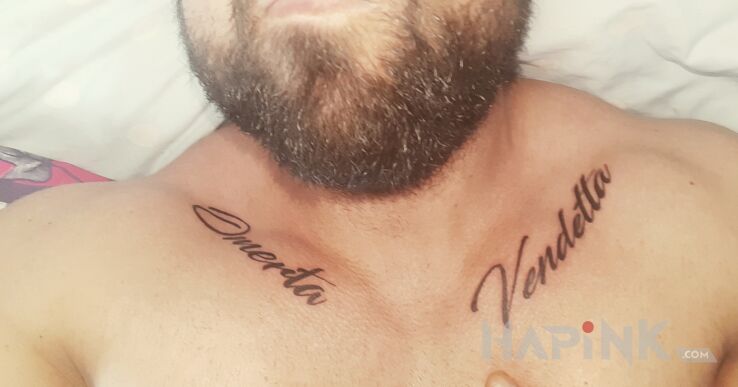 Tattoo Omerta i Vendetta in lettering motif and calligraphy style on the collarbone