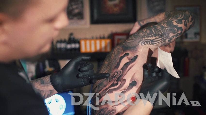 Tatuażysta smarujący kremem tatuaż na żebrach