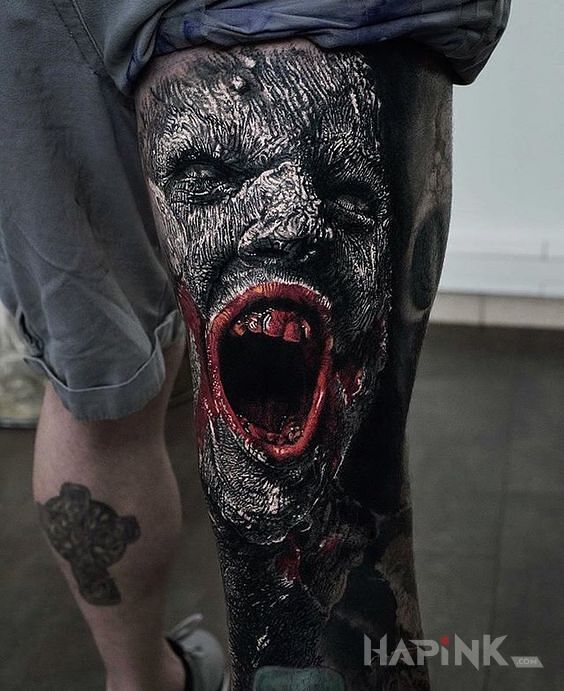 Tattoo Krzyk rozpaczy in faces motif and realistic style on the leg