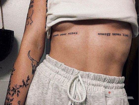 Tattoo Pozytywne wibracje in lettering motif and calligraphy style on the stomach