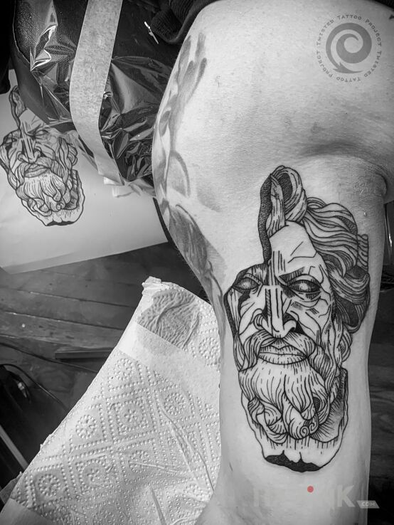 Tattoo Zeus in faces motif and graphic / illustrative style on the upper arm