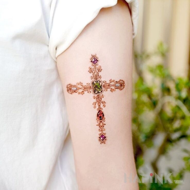 Tattoo Krzyżyk in colorful motif and realistic style on the upper arm