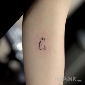 Tattoo A very small penguin on the upper arm motif: black and gray style: minimalistic