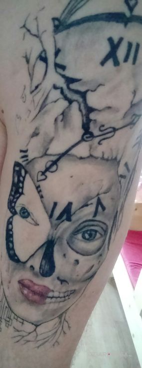 Tatuaż twarz kobiety i zegar w motywie twarze na ramieniu