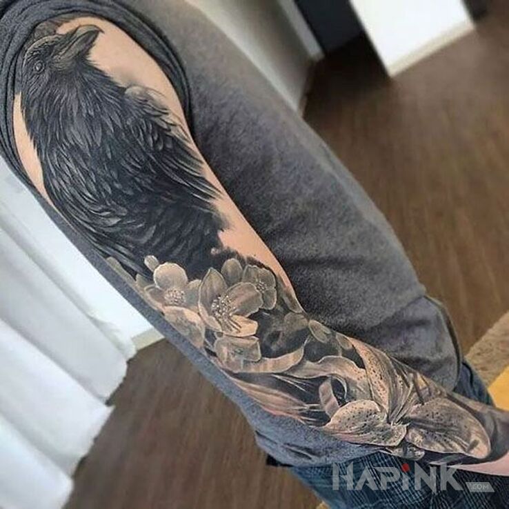 Tattoo Kruk czuwa in flowers motif and realistic style on the upper arm