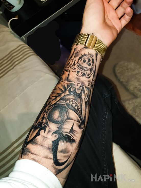 Tattoo Joker z kartą śmierci in faces motif and chicano style on the forearm