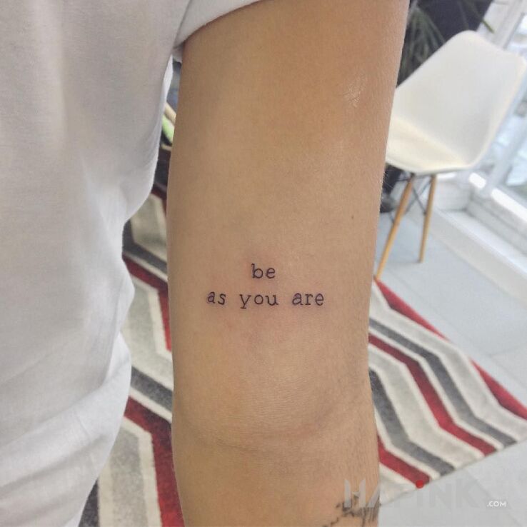 Tattoo Be as you are in lettering motif and calligraphy style on the upper arm