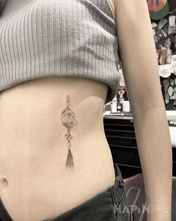 Tattoo Wisiorek in black and gray motif and graphic / illustrative style on the ribs