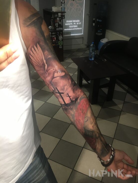 Tattoo Golgota in sleeves motif and realistic style on the upper arm