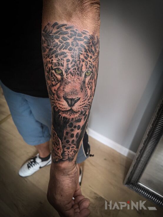 Tattoo Skradający się lampart in black and gray motif and realistic style on the forearm