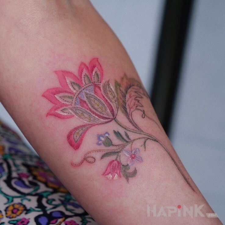 Tattoo Delikatny kwiat in colorful motif and embroidered style on the forearm