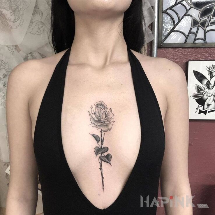 Tattoo Róża in black and gray motif and graphic / illustrative style between the breasts