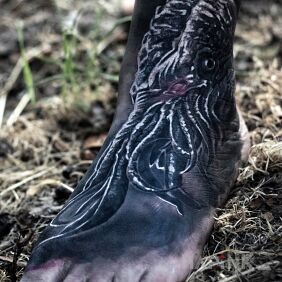 Tattoo Cthulhu on the foot motif: black and gray style: realistic