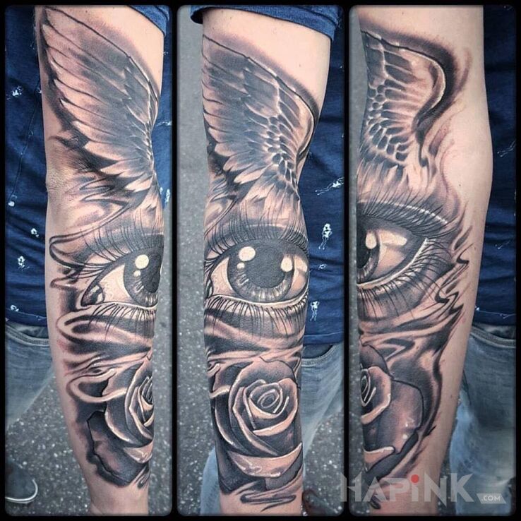 Tattoo Skrzydlate oko in flowers motif on the upper arm