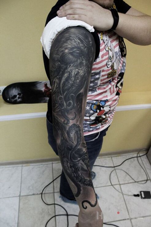 Tattoo Culthu in characters motif and realistic style on the upper arm