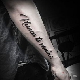 Tattoo Nunca te rindas on the forearm motif: lettering style: calligraphy