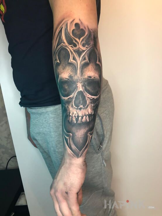 Tattoo Czaszka z ornamentami in skulls motif and realistic style on the forearm