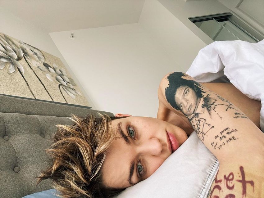 kobieta z tatuażem na ramieniu leżąca w łóżku