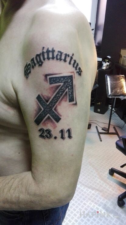 Tattoo Strzelec (nieskończony) in zodiac signs motif and calligraphy style on the upper arm