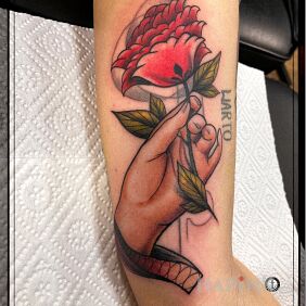 Tattoo A woman's hand with a flower on the upper arm motif: colorful style: neo-traditional