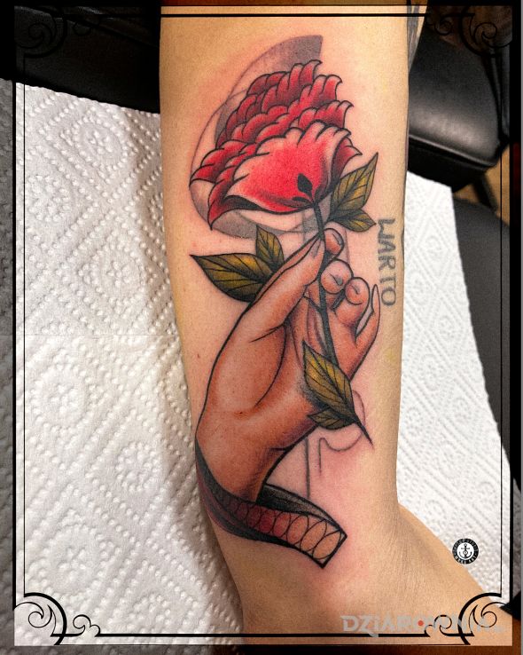Tatuaż kobieca dłoń z kwiatem w motywie kwiaty i stylu neotradycyjne na ramieniu