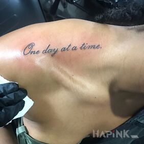 Tattoo One day at a time on the collarbone motif: lettering style: calligraphy