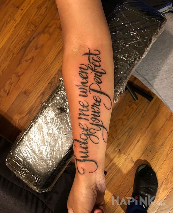 Tattoo Ocenianie innych ludzi in lettering motif and calligraphy style on the forearm