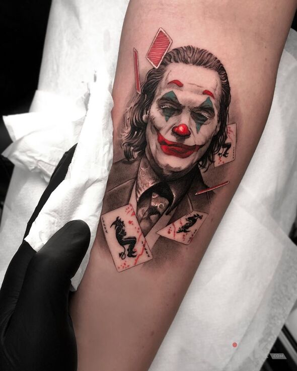 Tattoo Joker pośród kart in characters motif and realistic style on the forearm