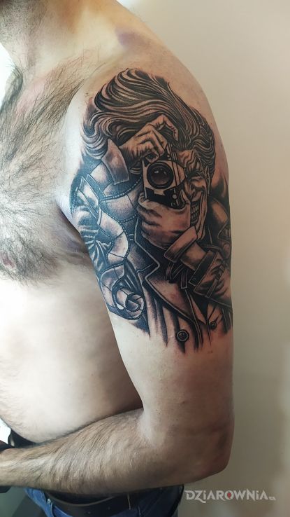 Tatuaż joker z aparatem w motywie czarno-szare i stylu kreskówkowe / komiksowe na ramieniu