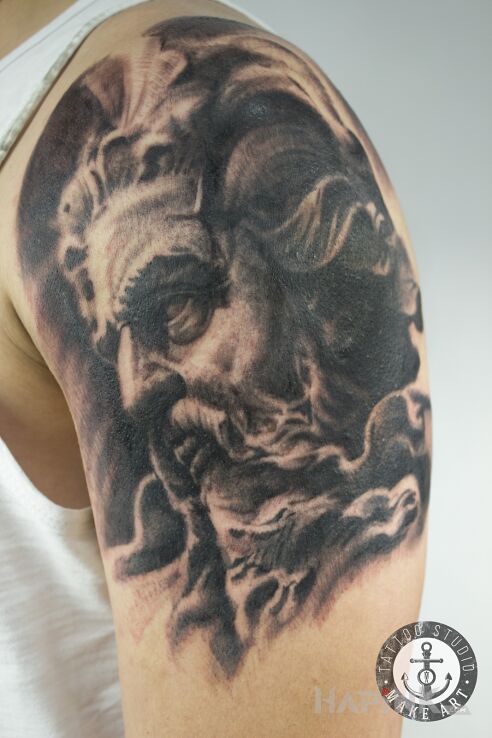 Tattoo Zeus in black and gray motif and realistic style on the upper arm