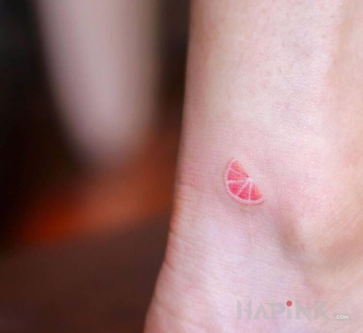 Tattoo Kawałek grejfruta in colorful motif and minimalistic style near the ankle