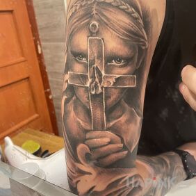 Tattoo Woman with a cross on the upper arm motif: black and gray style: white ink