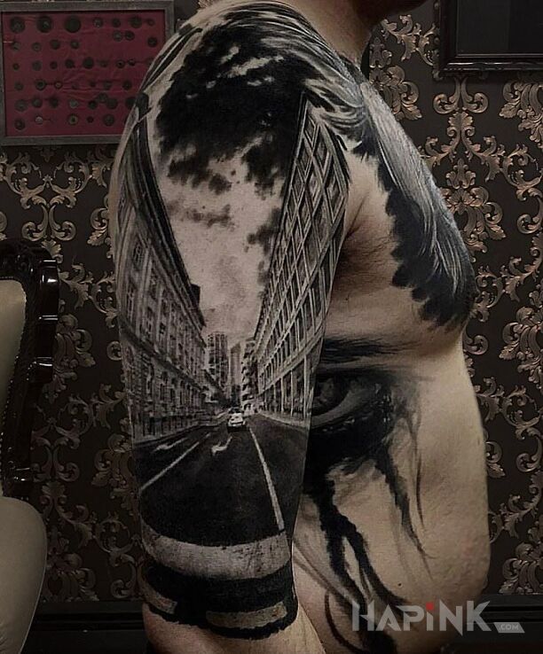 Tattoo Na ulicy in black and gray motif and realistic style on the upper arm