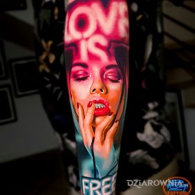Tatuaż Love is Free na przedramieniu motyw: napisy styl: realistyczne