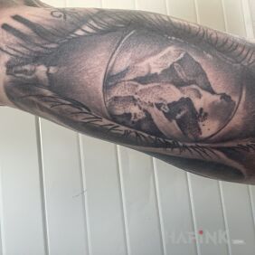 Tattoo Mountains in the eye of the clock on the upper arm motif: nature style: realistic